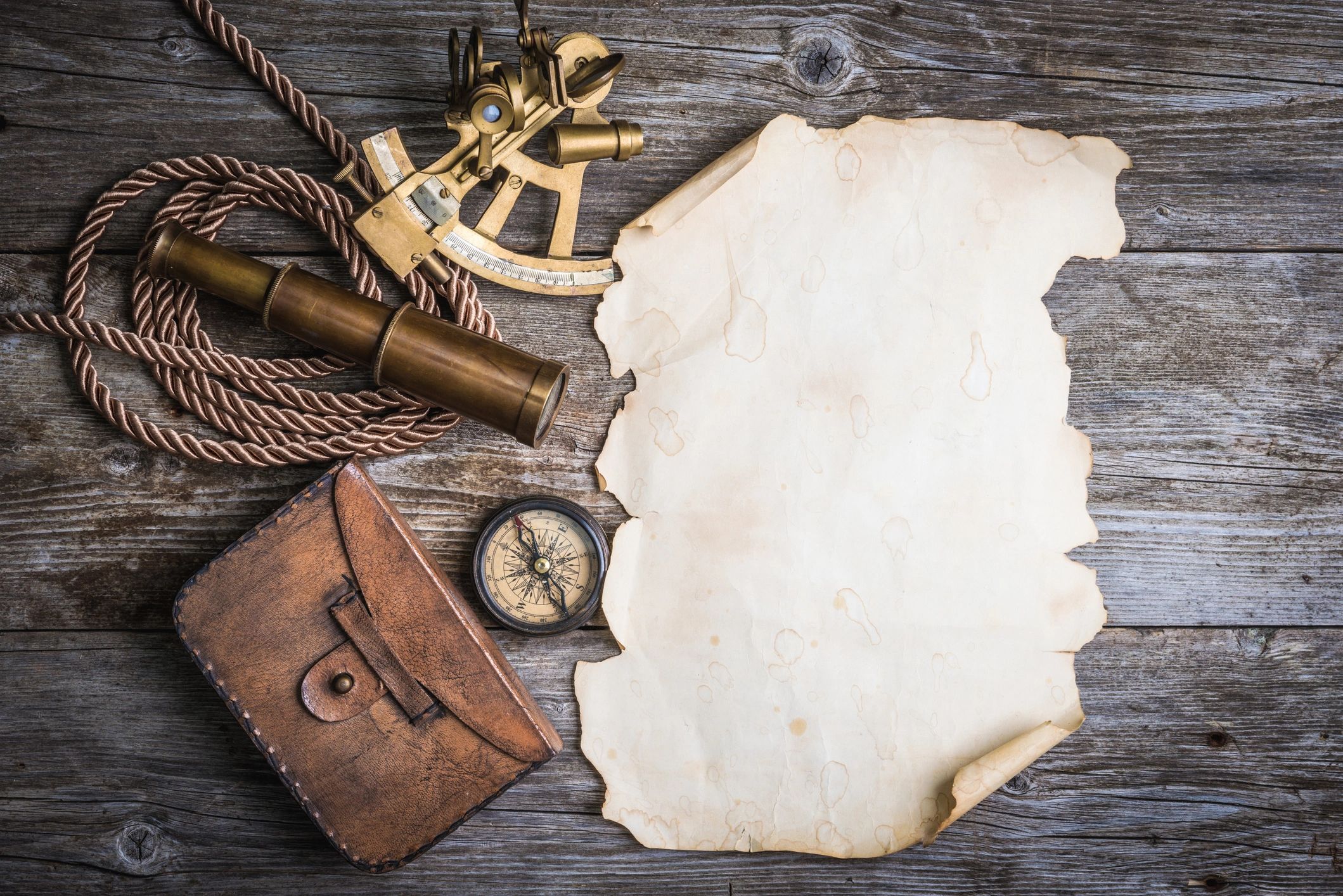 Parchment map with compass and spyglass on a wooden table