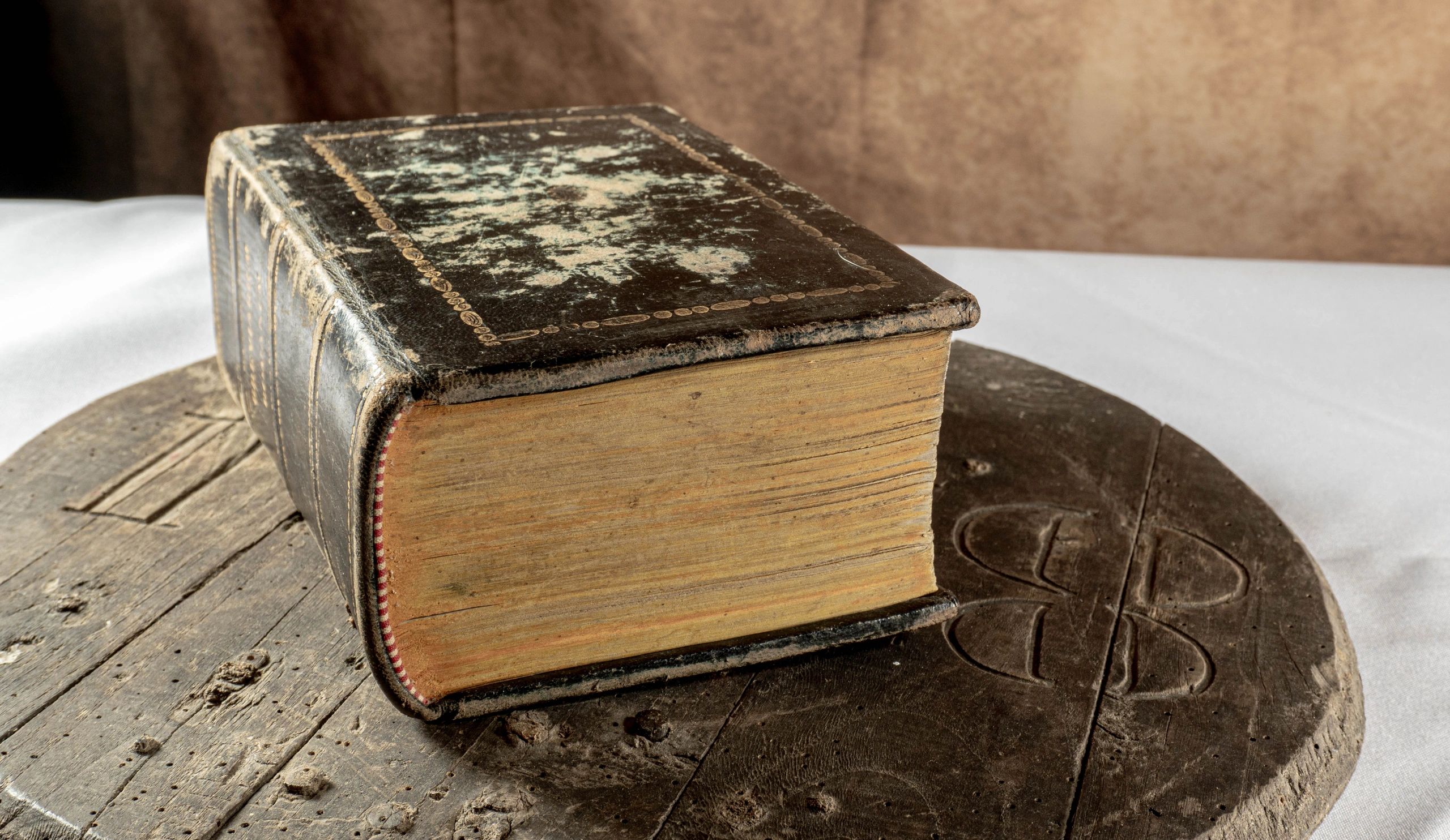 A very old and worn book resting on rustic wood